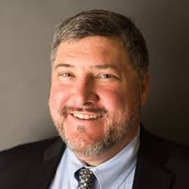 Smiling man in a suit with a beard.