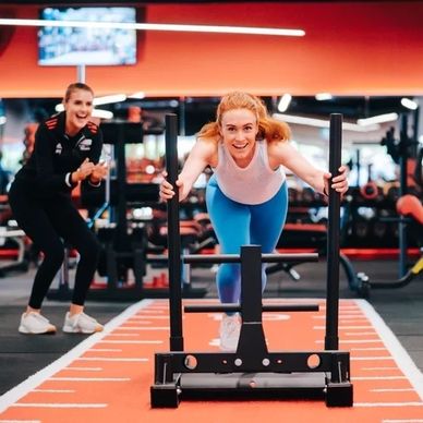 Woman pushing a weighted sled in the gym.